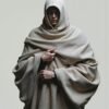 A dramatic portrait of a figure in a dove-gray hooded cloak, with sculptural fabric folds and an intense gaze, captured in minimalist fashion photography.