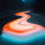 A winding river illuminated in vibrant hues of orange, pink, and blue flows through a dark, mountain landscape, creating a captivating abstract vision of nature’s beauty.