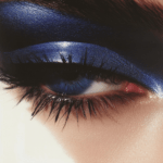 A striking eye adorned with shimmering blue eyeshadow, emphasizing depth, intensity, and the art of makeup.