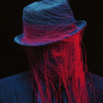 A figure with a shrouded face, vibrant blue and red strands flowing from a stylish hat, set against a dark background, symbolizing the complexity of identity and perception.